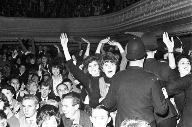 Admin_thumb_fans_at_the_beatles_concert__wellington_town_hall__june_1964._shows_some_standing_and_screaming__being_held_back_by_policemen._other_people_are_seated_nearby._photograph_taken_by_morrie_hill_of_wellington